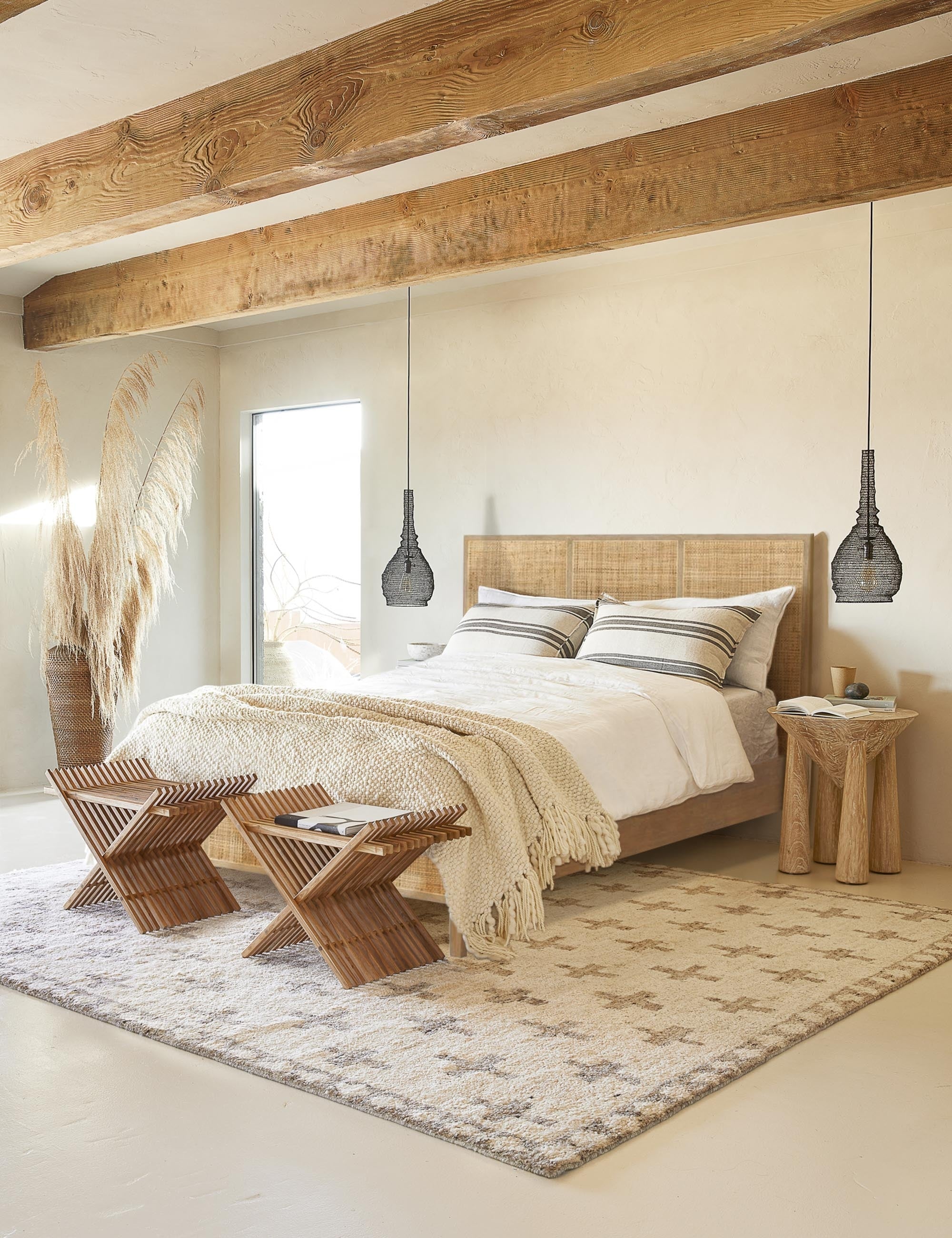 #size::king #size::queen #color::natural | The Hannah bed with light wood cane bed frame sits in a bright bedroom with a plush patterned rug beneath it and wooden ceiling beams above it.