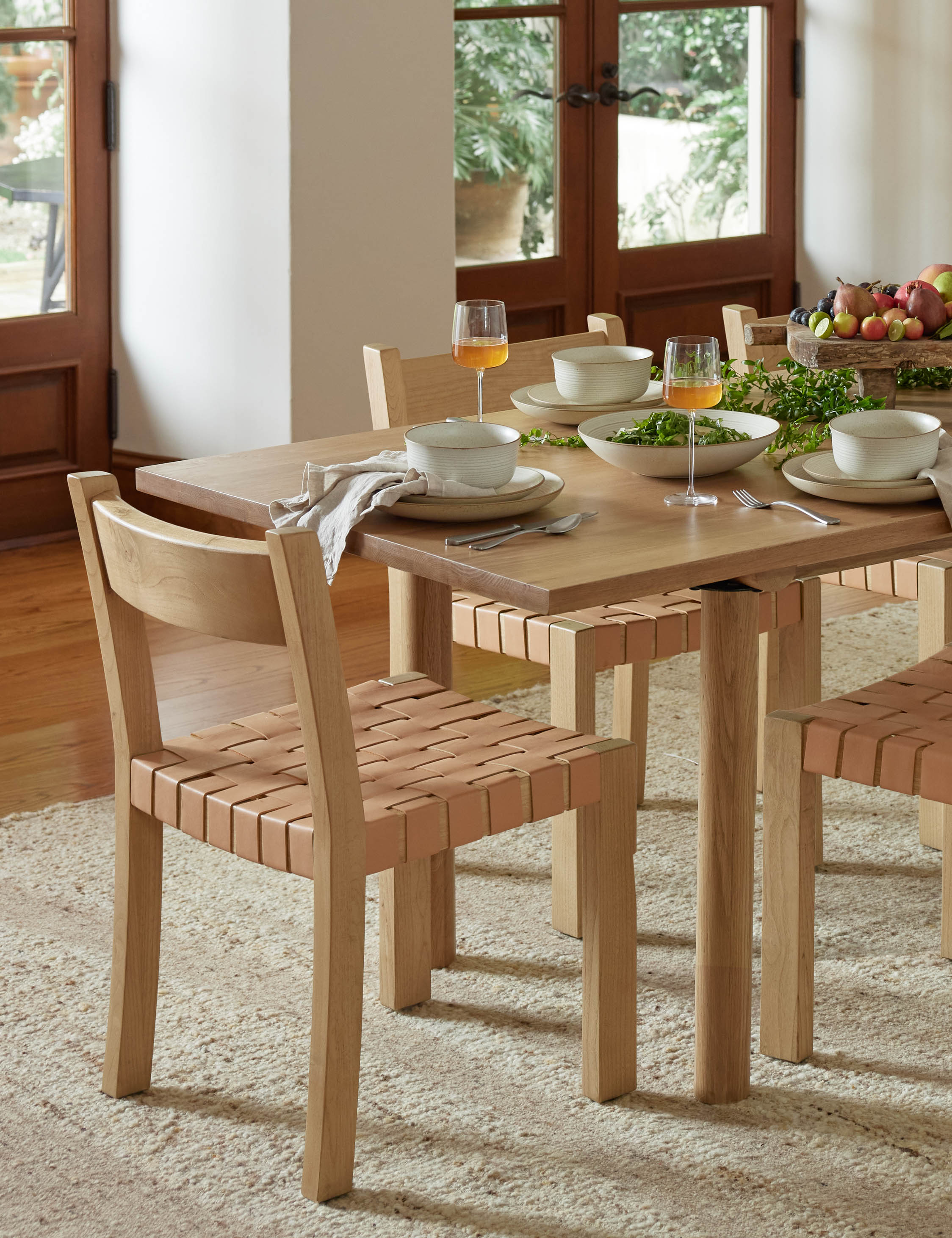 #color::natural | Vix light wood frame and woven leather seat dining chair styled with a light wood dining table and natural ivory rug.