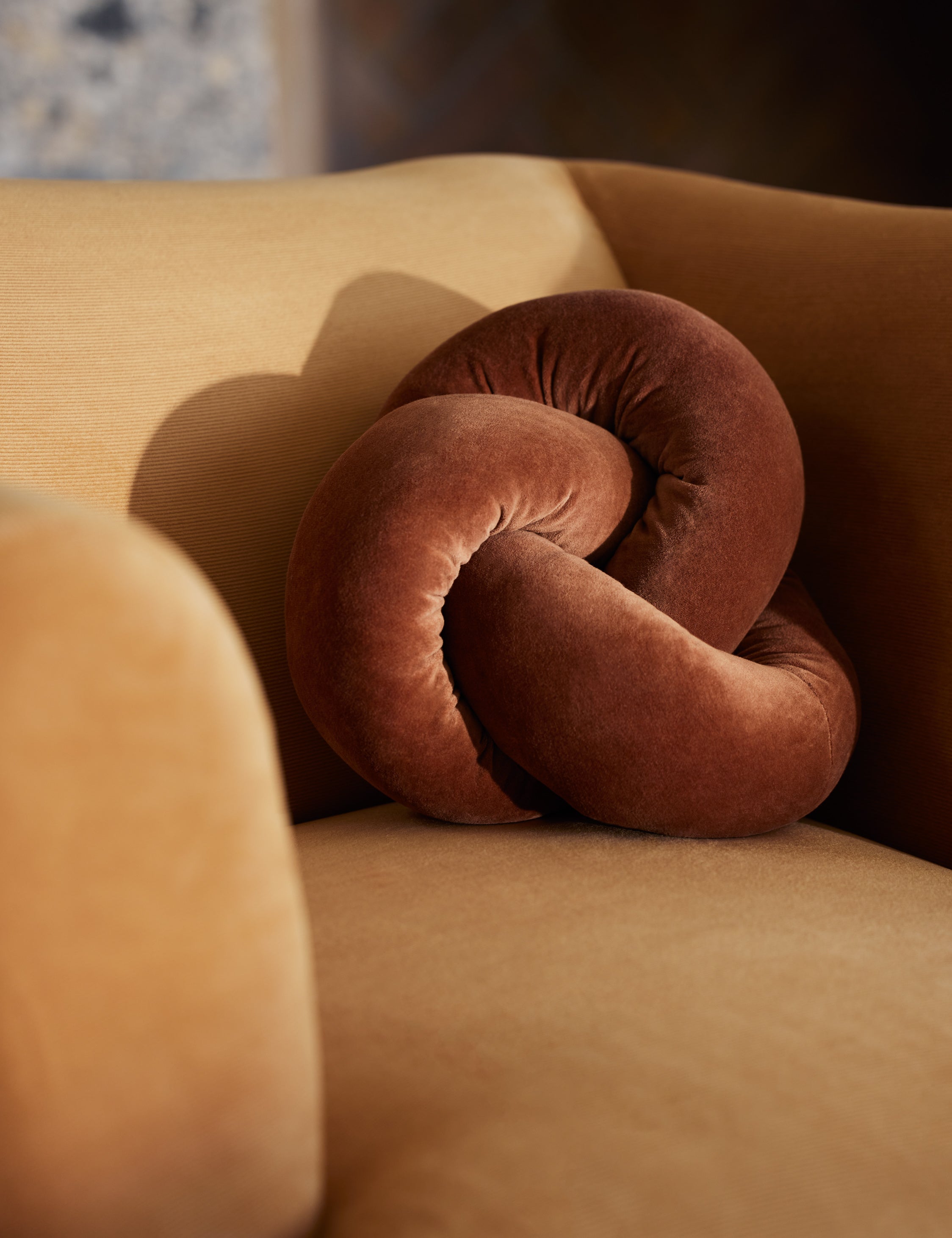 #color::burnt-orange | The Dewey velvet knot ball pillow styled on an accent chair.