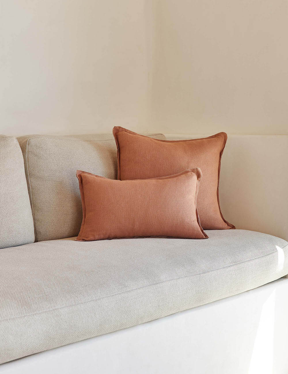 #color::rust #style::square #fill type::with-feather-down-insert #fill type::pillow-cover-only | The arlo rust orange flax linen pillow in its lumber and square sizes sit together on a natural linen sofa