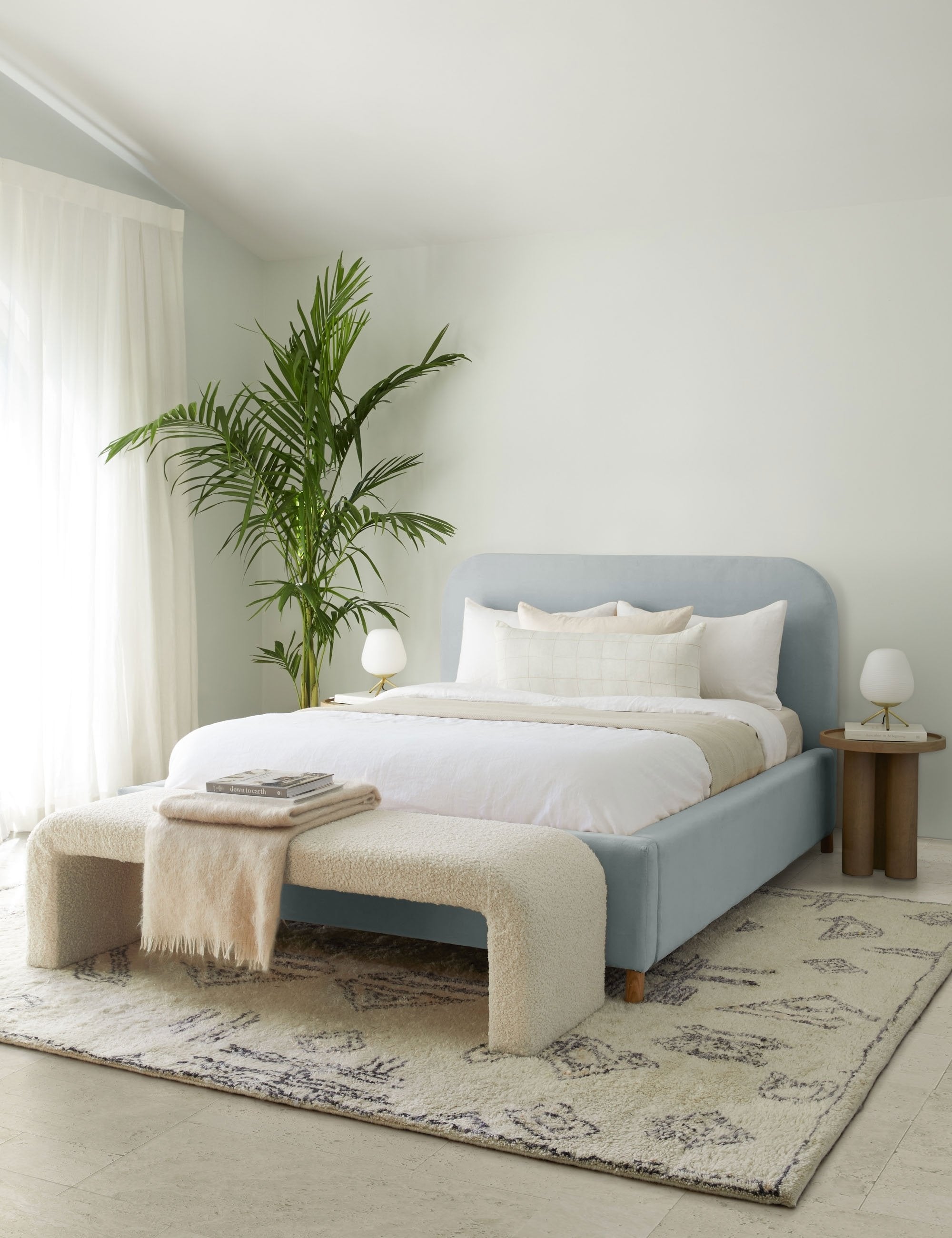 #showall::L0458517 | The Solene dove light blue velvet platform bed sits atop a plush patterned rug with a boucle cream bench and white linens